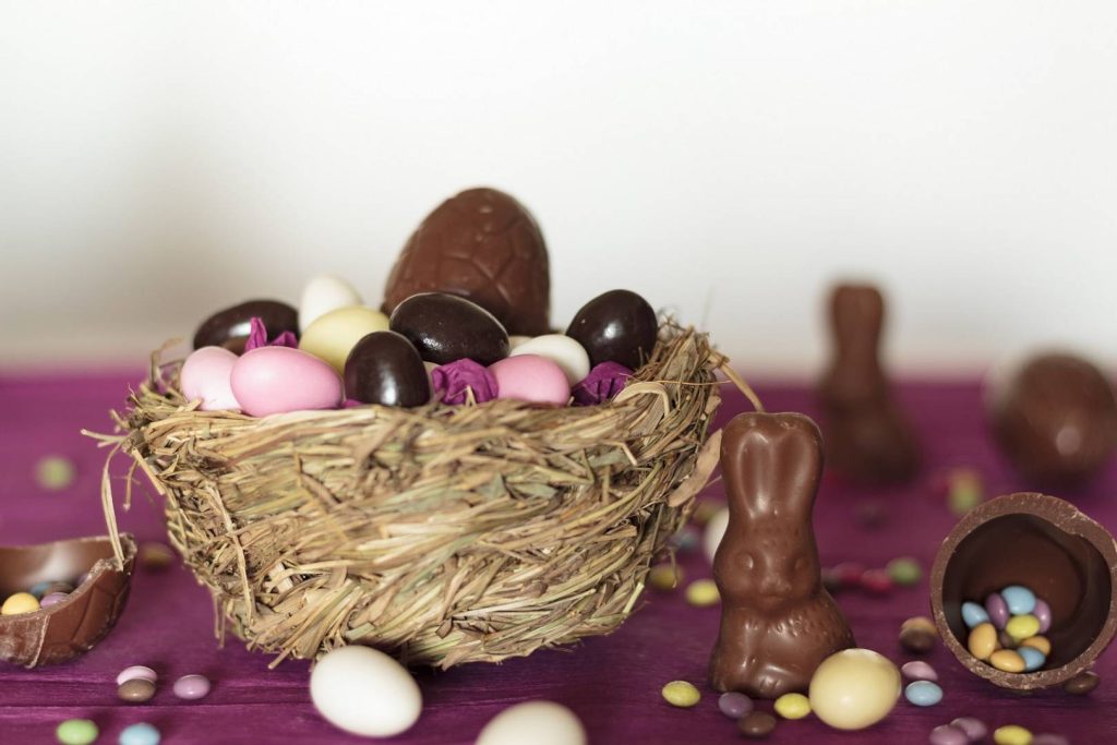 Nest with chocolate eggs, chocolate bunny and sweets on easter table