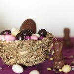 Nest with chocolate eggs, chocolate bunny and sweets on easter table